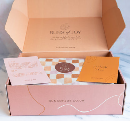 Beautifully printed gift box, with a personalised greetings card. Printed in pink and orange with a checkerboard greaseproof paper holding the cinnamon buns.