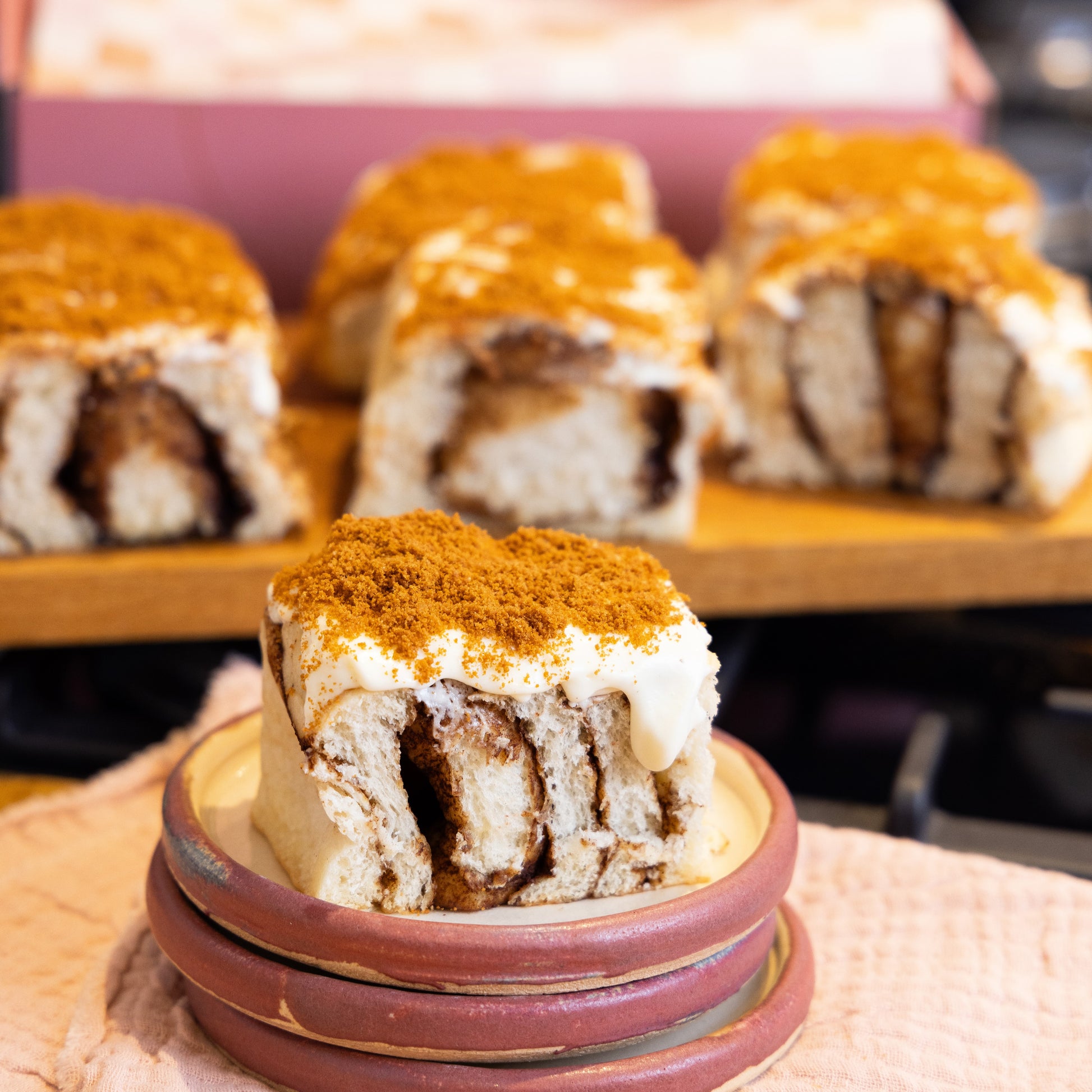 a Biscoff cheesecake bun on a stack of pink plates with 6 more Biscoff cheesecake buns in the background