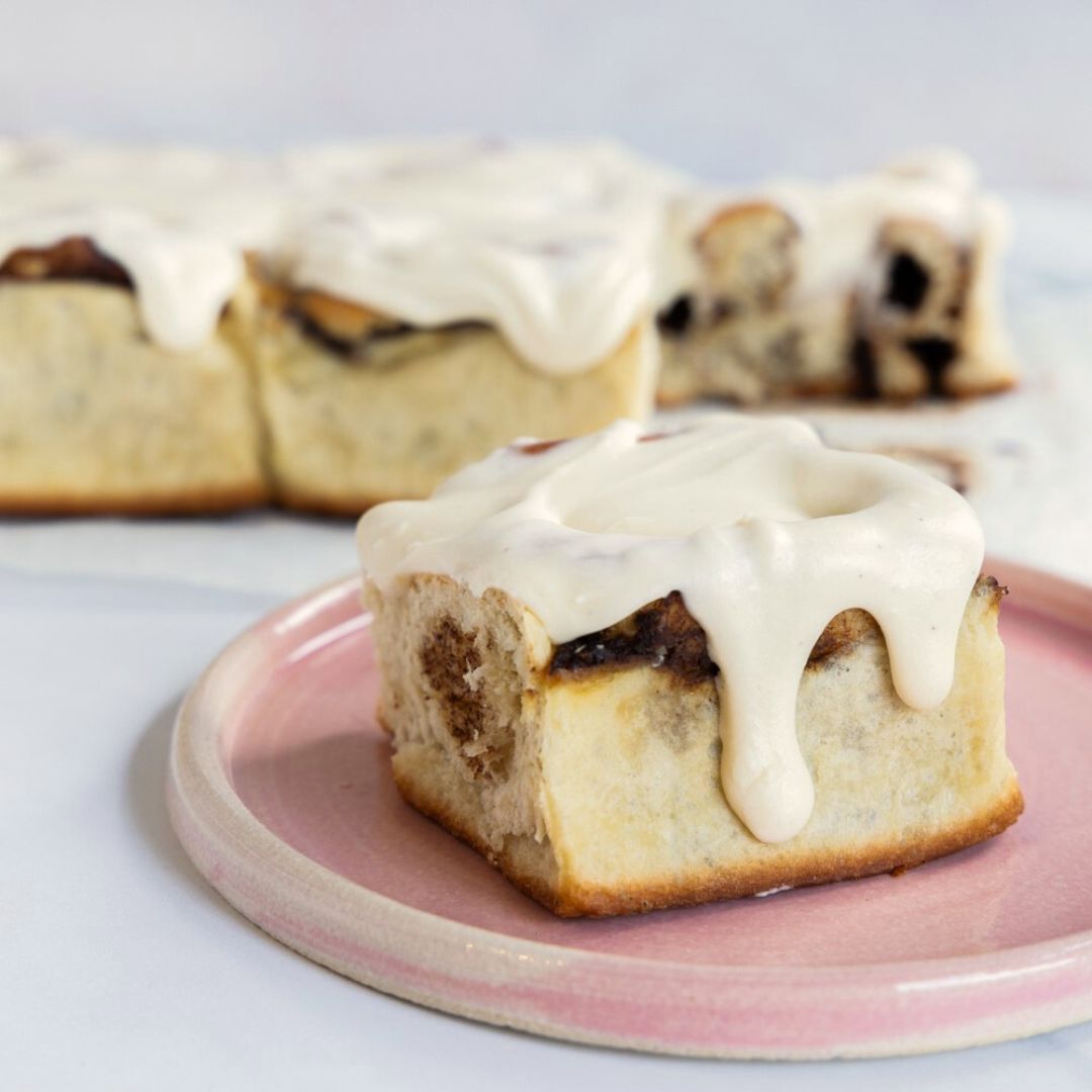 cinnamon bun on a plate with delicious dripping cream cheese frosting