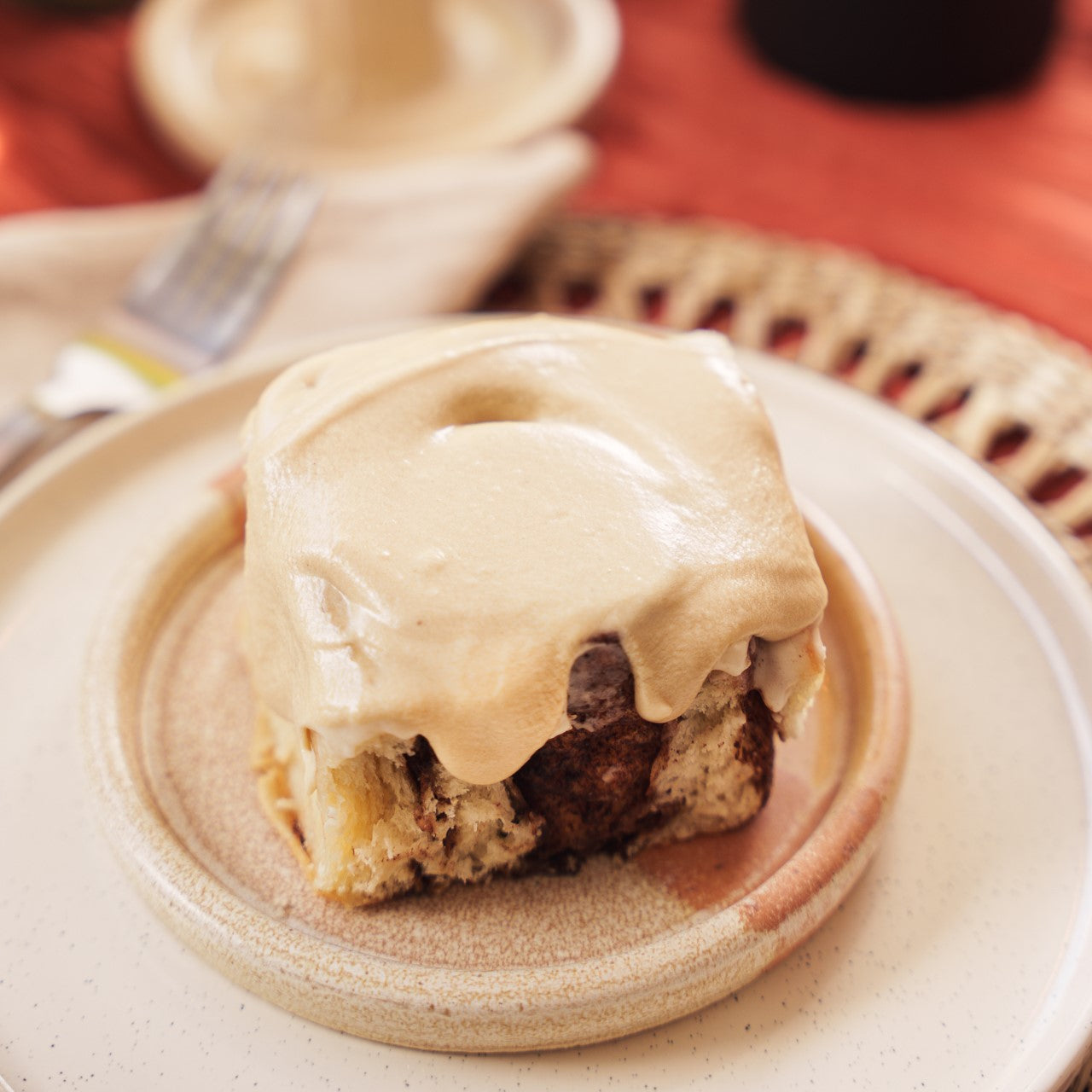 Picture of a spiced bun with latte coffee cream cheese icing on a natural coloured plate