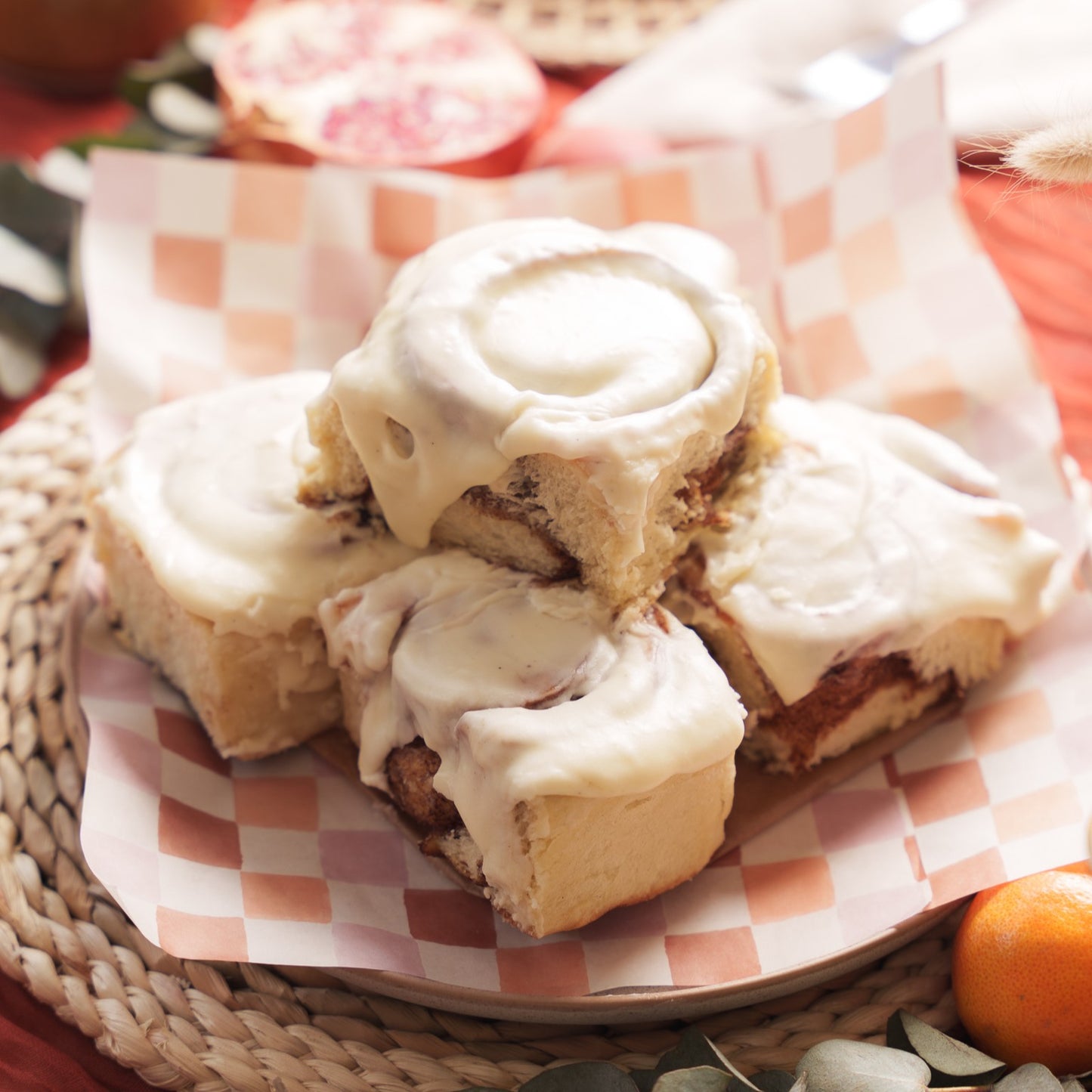 Stack of Cinnamon Buns on a plate with checkerboard greaseproof paper underneath